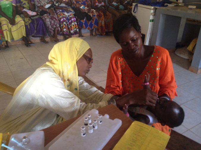 Maimouna giving the oral polio vaccine to an infant
